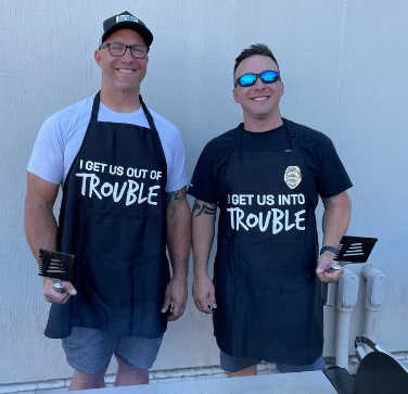Trademark Global team members host a company party, where two team leaders wear fun aprons while manning the grill.
